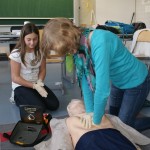 Schülerinnen üben das Wiederbeleben mit dem Defibrilator